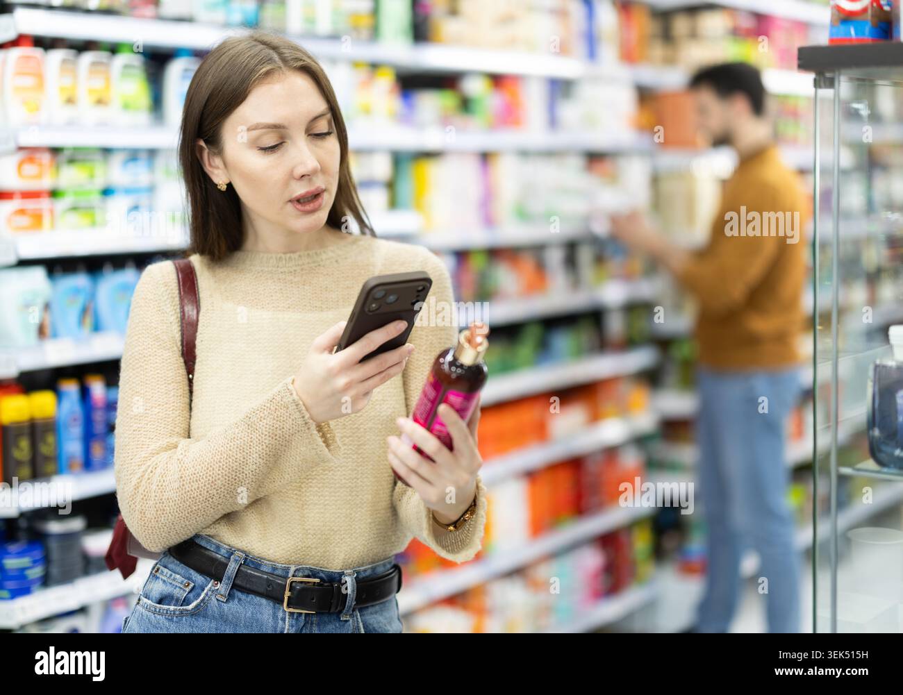 Acquirente donna che esegue la scansione del codice qr per shampoo o gel doccia in un negozio di prodotti chimici per uso domestico Foto Stock