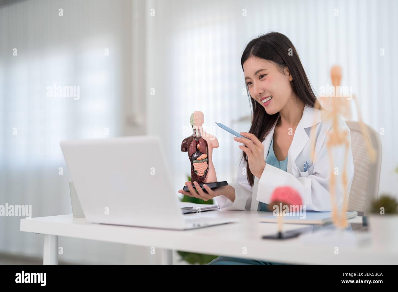 Giovane donna asiatica medico dimostrando il modello di anatomia dell'organo interno mentre l'insegnamento presso la clinica medica ufficio scrivania Foto Stock