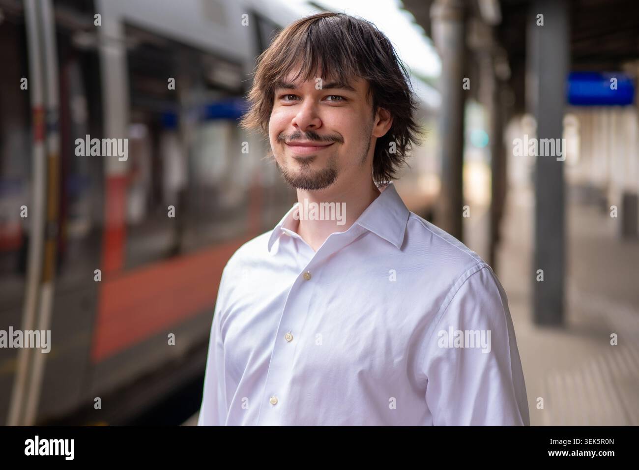 Ritratto positivo di un giovane con la barba alla stazione ferroviaria in Austria Foto Stock
