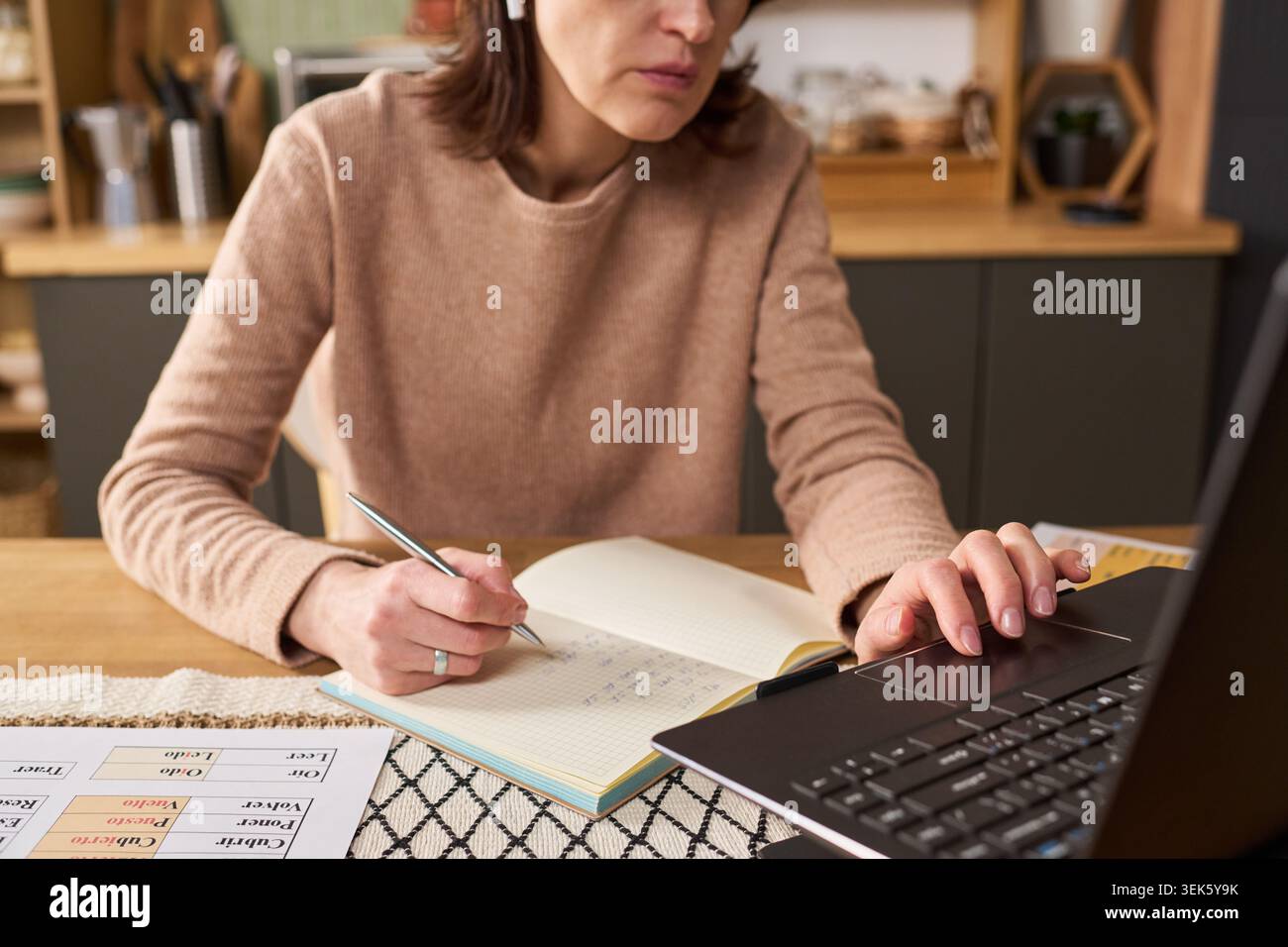 Donna di mezza età che impara online e prende appunti a casa Foto Stock