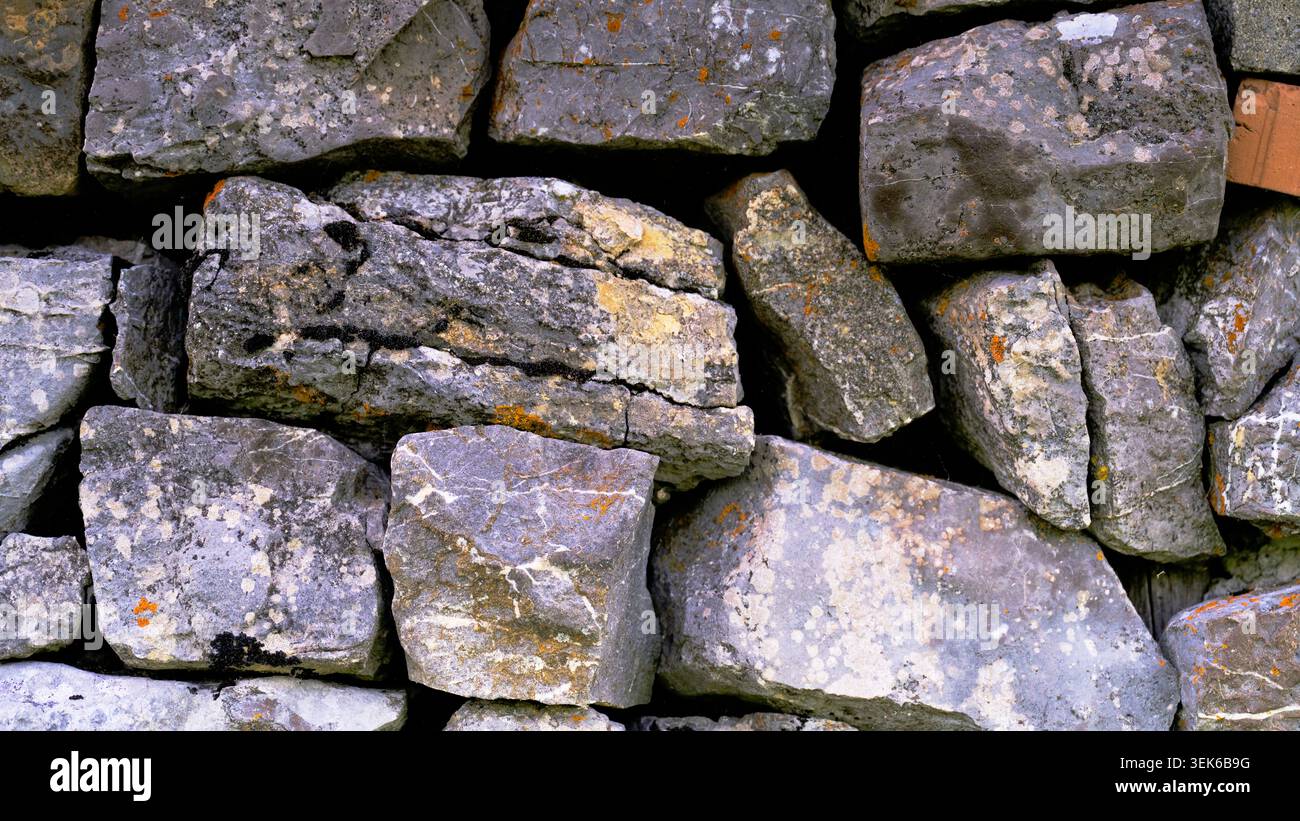Le rocce impilate insieme formano una parete robusta in un ambiente all'aperto durante le ore di luce diurna Foto Stock