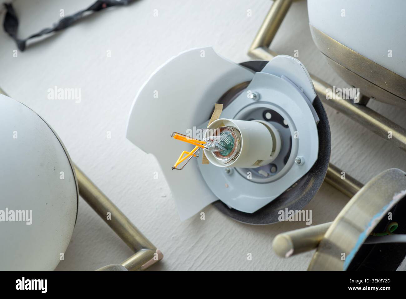 Paralume in vetro rotto su un lampadario da soffitto con fili esposti e presa di luce interna Foto Stock