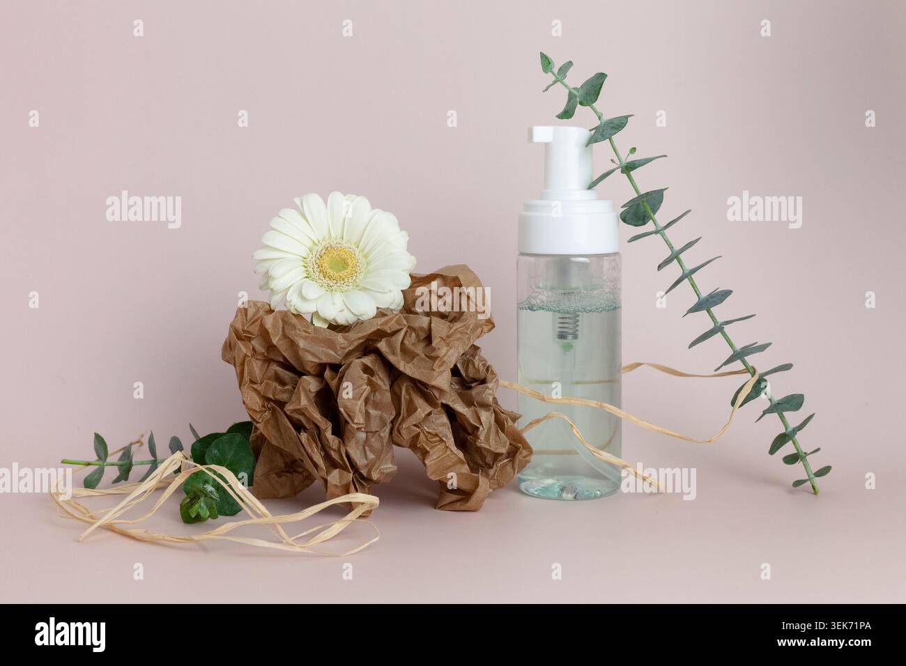 Dispenser per schiuma cosmetica naturale con fiore ed eucalipto su sfondo rosa Foto Stock