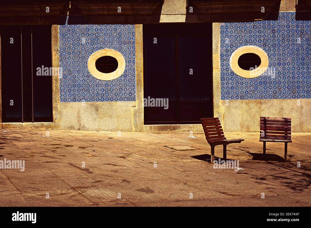 Dettagli architettonici con piastrelle azulejo portoghesi tradizionali blu, finestre circolari e panchine in una tranquilla piazza urbana. Foto Stock