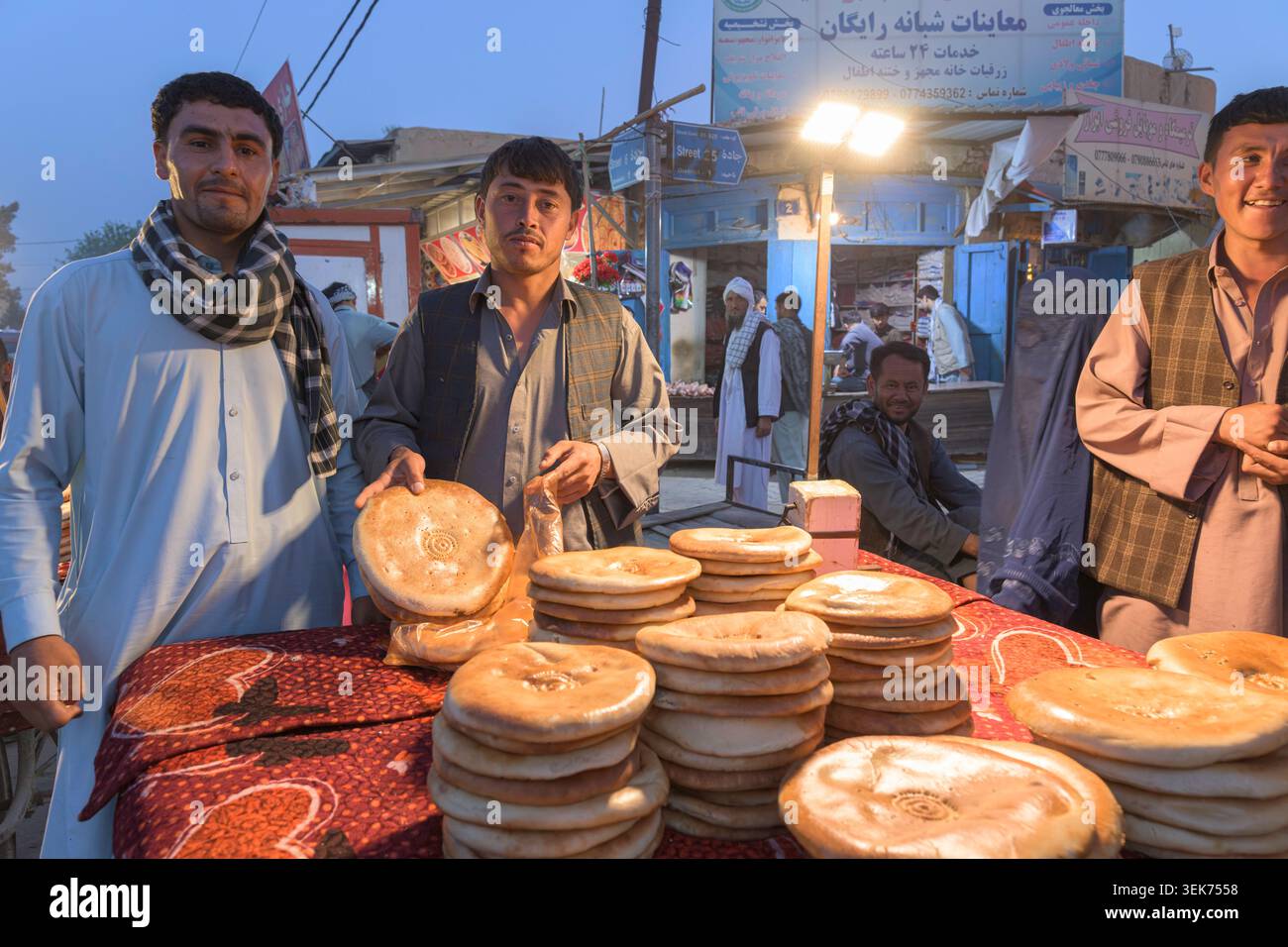 Venditori ambulanti che gestiscono pane naan fresco in un mercato all'aperto a Samangan. Foto Stock