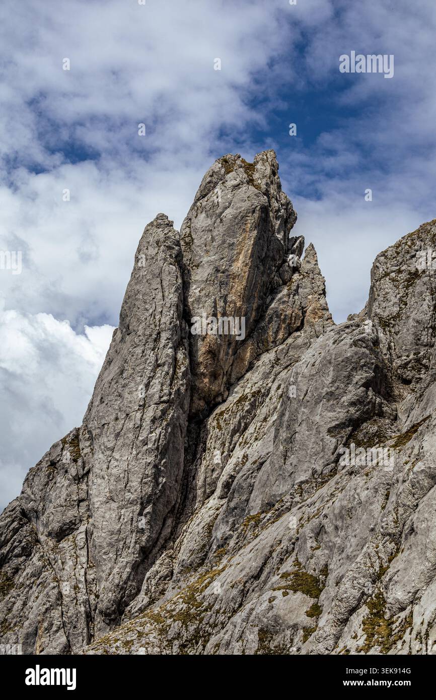 Una fotografia sorprendente cattura un'aspra vetta di montagna sullo sfondo di un cielo nuvoloso. Il picco, composto da roccia grigia, domina la cornice, showca Foto Stock