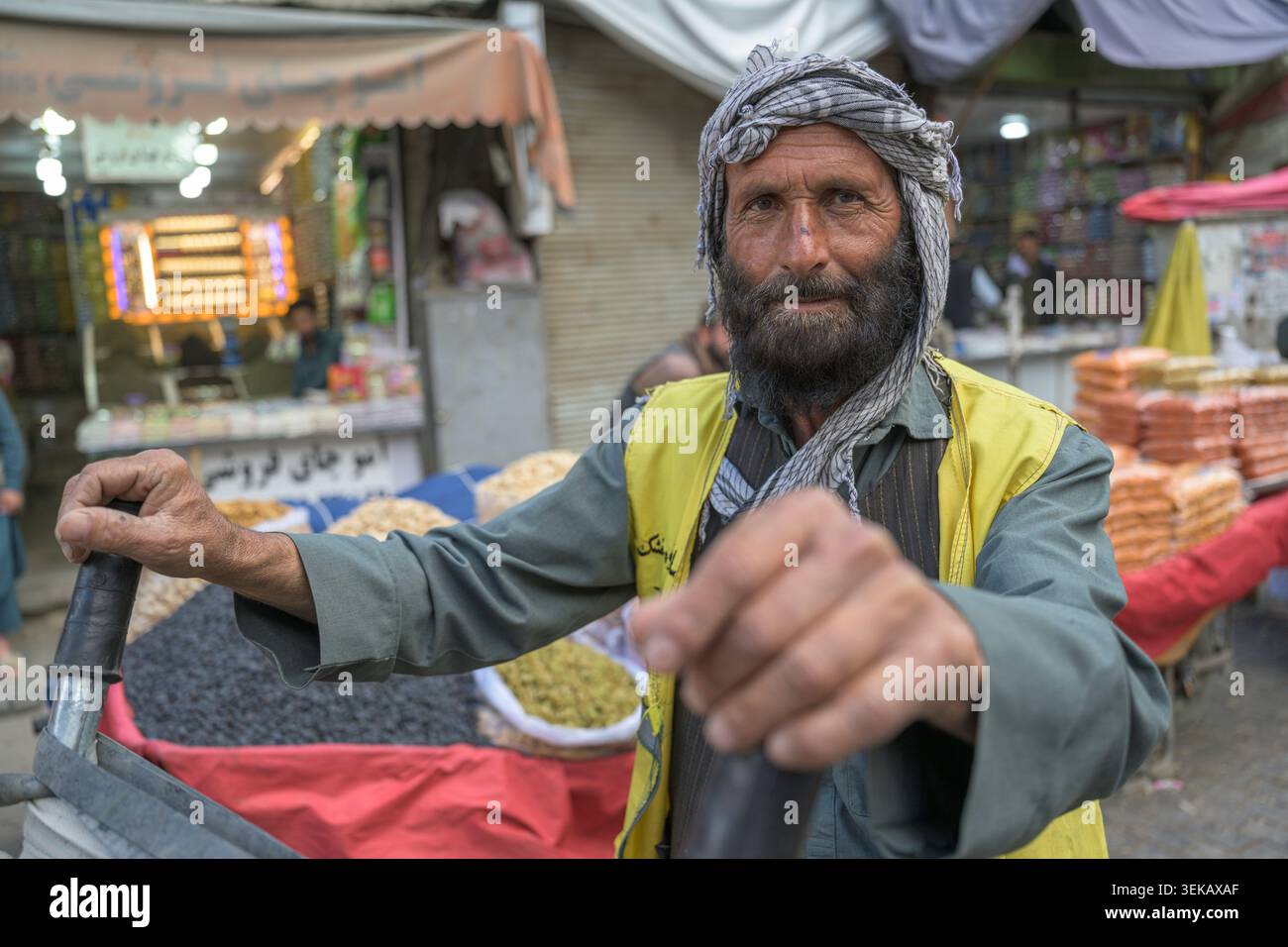 Portiere afghano che tiene il suo carro in una strada tranquilla del vecchio mercato di Kabul. Foto Stock