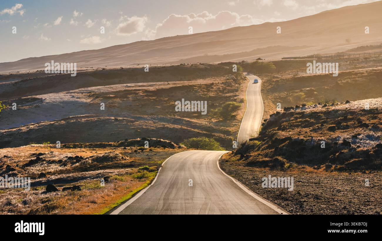 Strada tortuosa attraverso il paesaggio vulcanico bagnata dalla calda luce dorata al tramonto, Maui, Hawaii, Stati Uniti Foto Stock