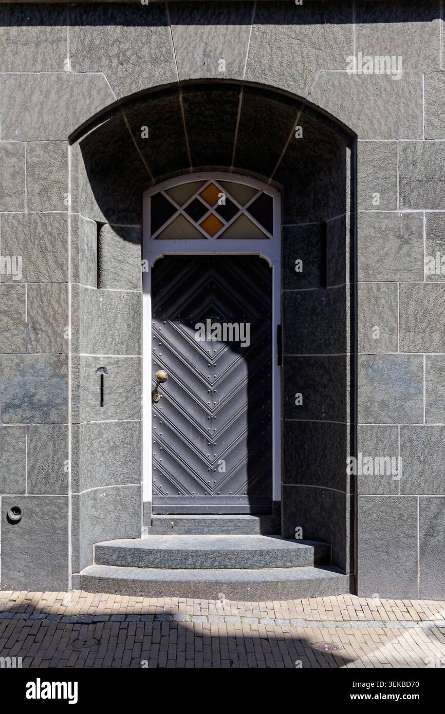 Porta d'ingresso geometrica scura nella facciata dell'edificio in pietra Foto Stock