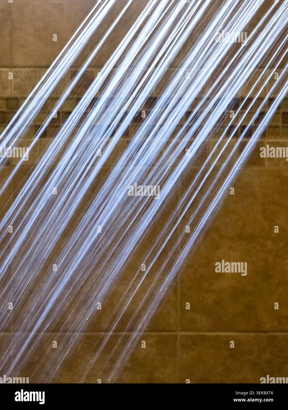Primo piano del flusso d'acqua della doccia su sfondo marrone piastrelle del bagno Foto Stock