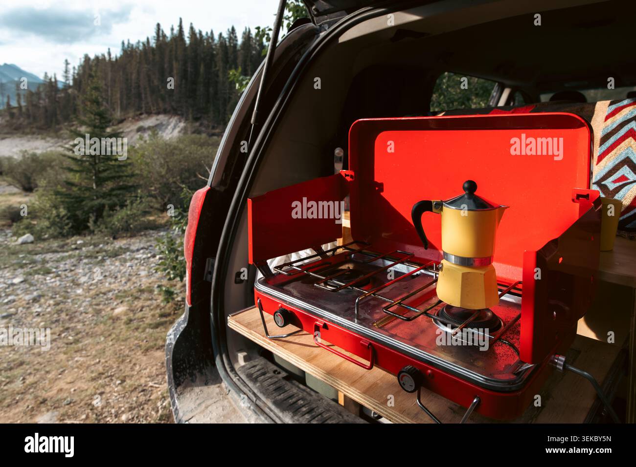 vista sul retro di un camper con una stufa rossa e una macchina per caffè espresso gialla in estate al mattino Foto Stock