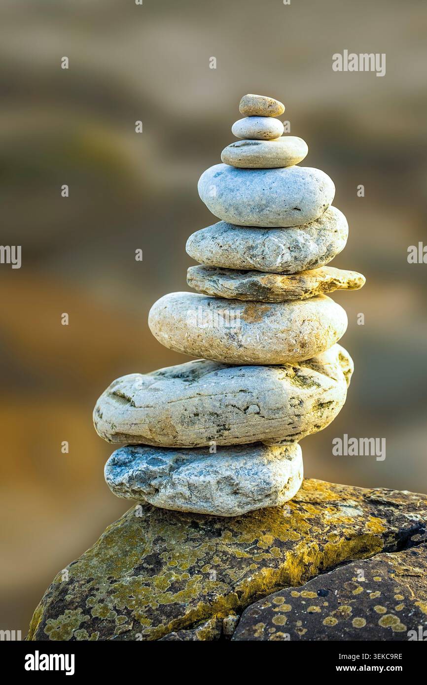 I ciottoli equilibrati sulla costa inglese simboleggiano il delicato equilibrio della natura, ricordandoci che la conservazione è fondamentale per preservare le nostre coste selvagge. Foto Stock