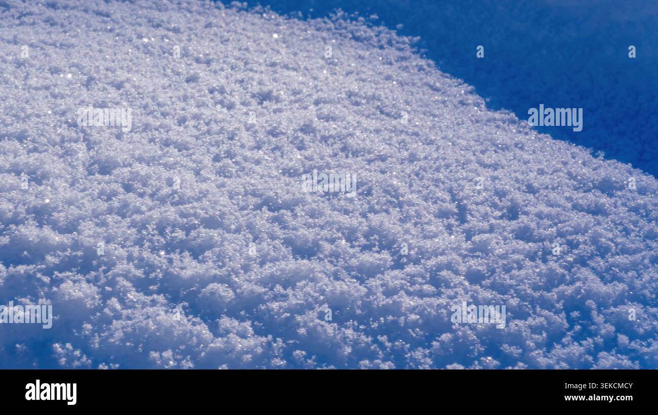 Primo piano di neve bianca pura che rivela la sua texture cristallina e scintillante sotto la luce del sole. Ideale per l'inverno e le vacanze. Foto Stock