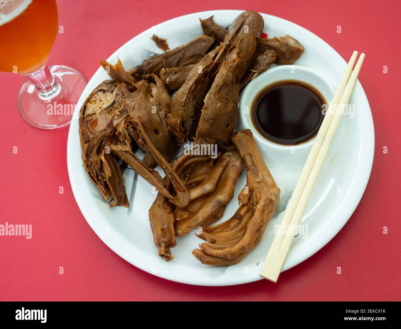 Una porzione di parti fritte bollite della carcassa d'anatra è disposta sul piatto - zampe, ali, testa. Foto Stock