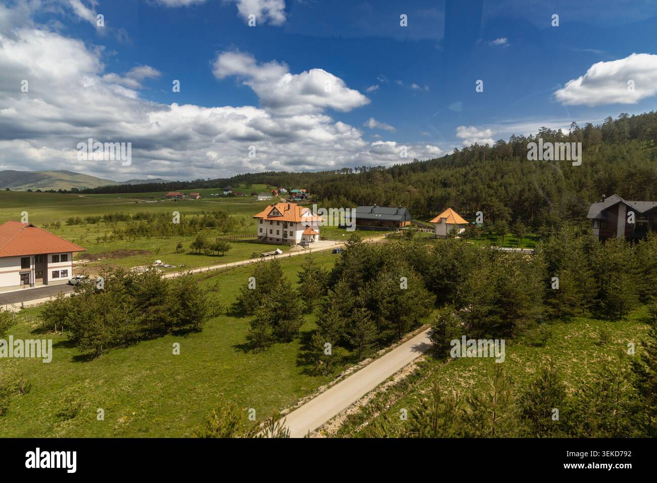 Serbia Zlatibor 24.05.2026 Case rurali tra campi verdi sotto cielo nuvoloso Foto Stock