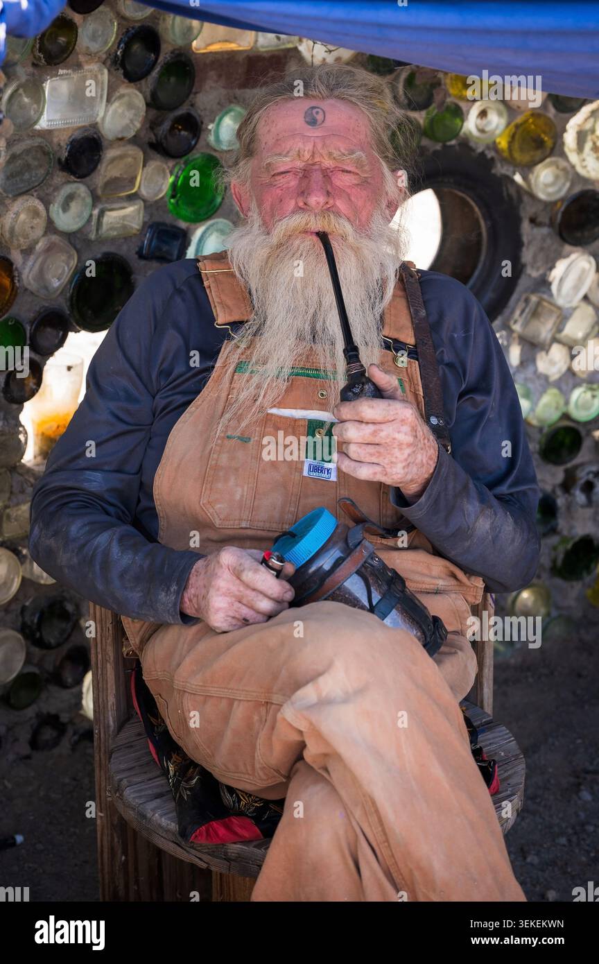 Un residente di lungo tempo e artista, conosciuto solo come il Mago, fuma la sua pipa. Gesù Est nella comunità informale degli artisti di Slab City, vicino al salto Foto Stock