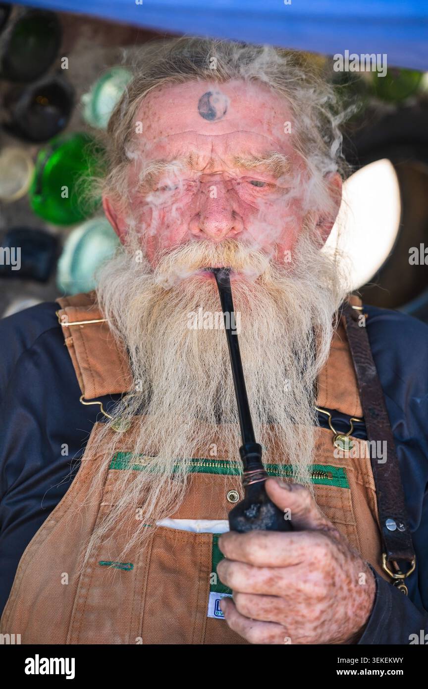 Un residente di lungo tempo e artista, conosciuto solo come il Mago, fuma la sua pipa. Gesù Est nella comunità informale degli artisti di Slab City, vicino al salto Foto Stock