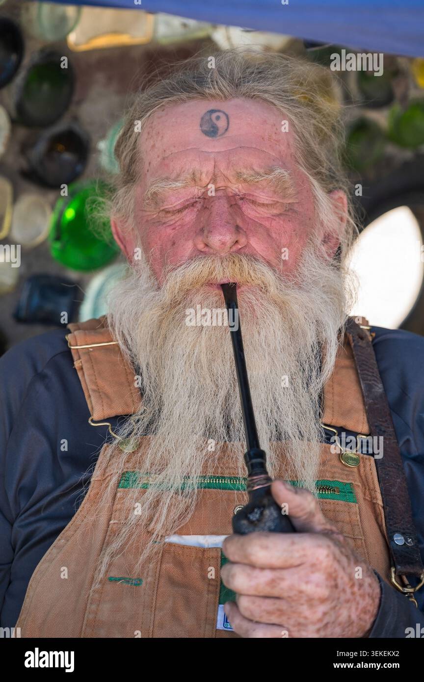 Un residente di lungo tempo e artista, conosciuto solo come il Mago, fuma la sua pipa. Gesù Est nella comunità informale degli artisti di Slab City, vicino al salto Foto Stock