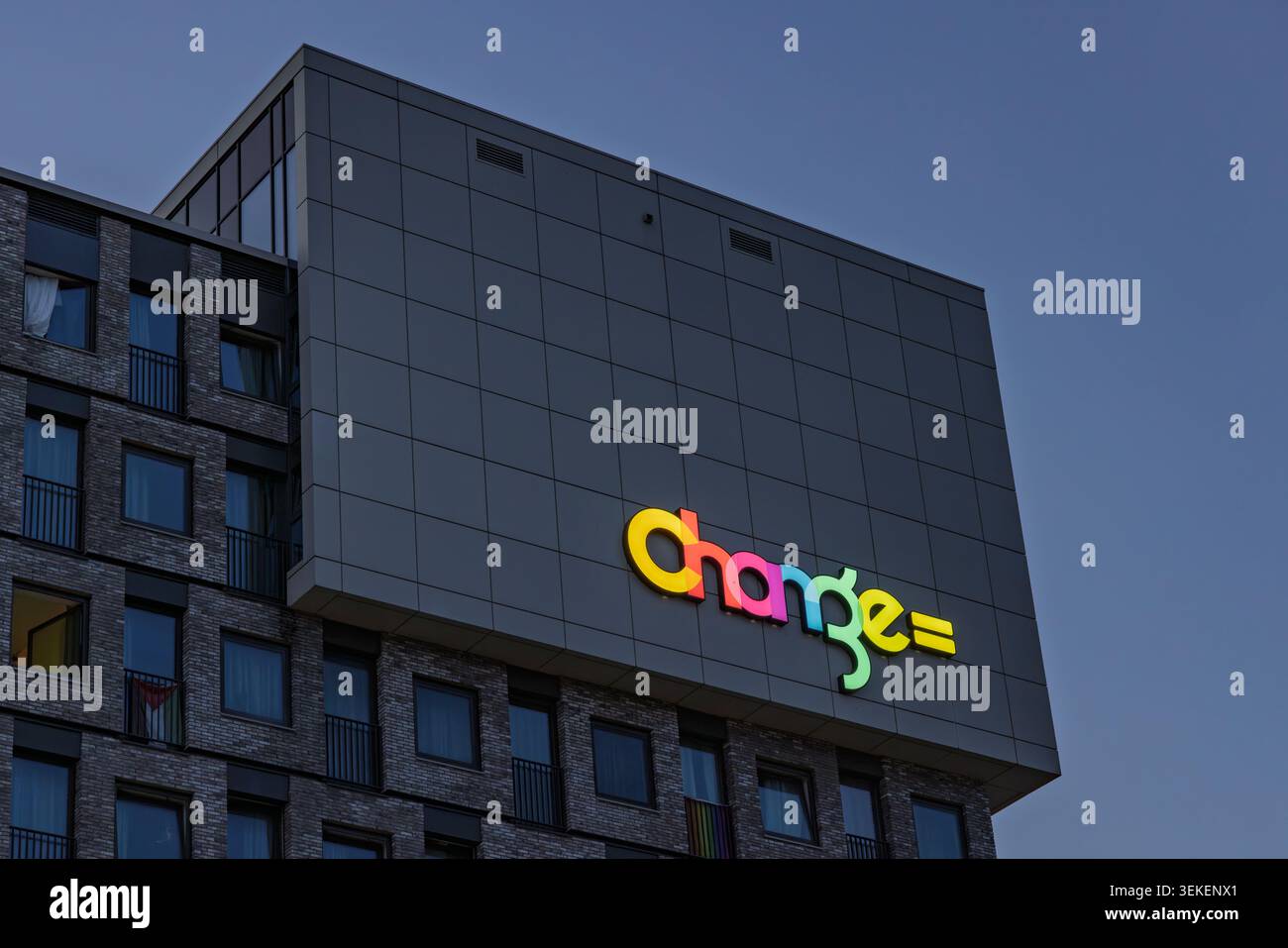 Amsterdam, Paesi Bassi: Vista notturna della facciata dell'edificio residenziale moderno con il suo logo luminoso e multicolore illuminato. Foto Stock