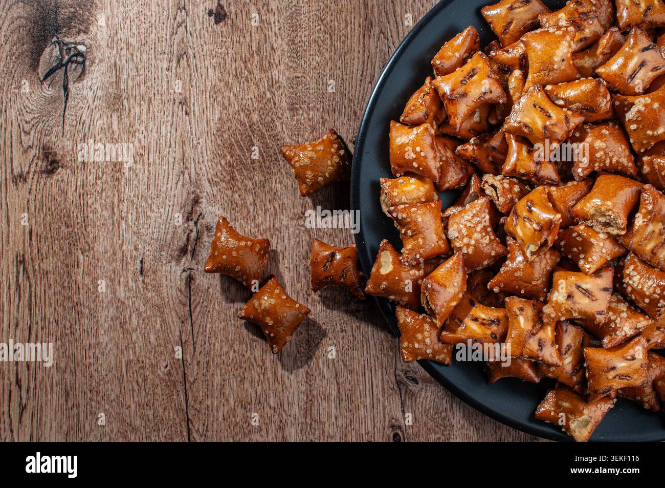 Pretzel a cubetti ripieni di burro di arachidi su un piatto nero su un rustico tavolo di legno. vista dall'alto, disporre uno spazio di copia piatto, orizzontale, riempito di cioccolato Foto Stock