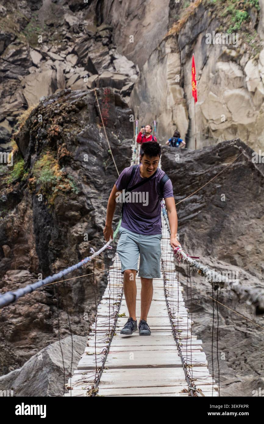 TIGER LEAPING GORGE, CINA - 10 NOVEMBRE 2019: Escursionista su un ponte sospeso sul fiume Jinsha nella Tiger Leaping Gorge, provincia dello Yunnan, Cina Foto Stock
