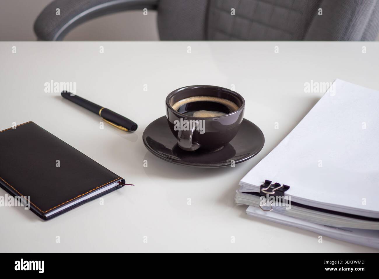 Spazio di lavoro minimalista con caffè, penna e notebook Foto Stock