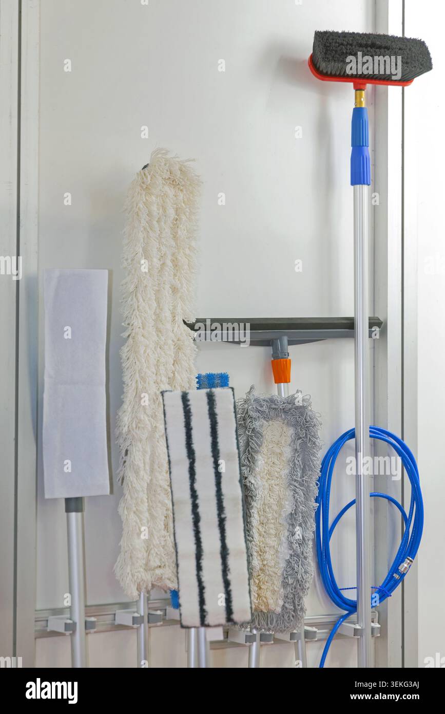 Organizzatore montato a parete per spazzatrici e portagomma per riporre utensili per la pulizia apparecchiature Utility Room Foto Stock