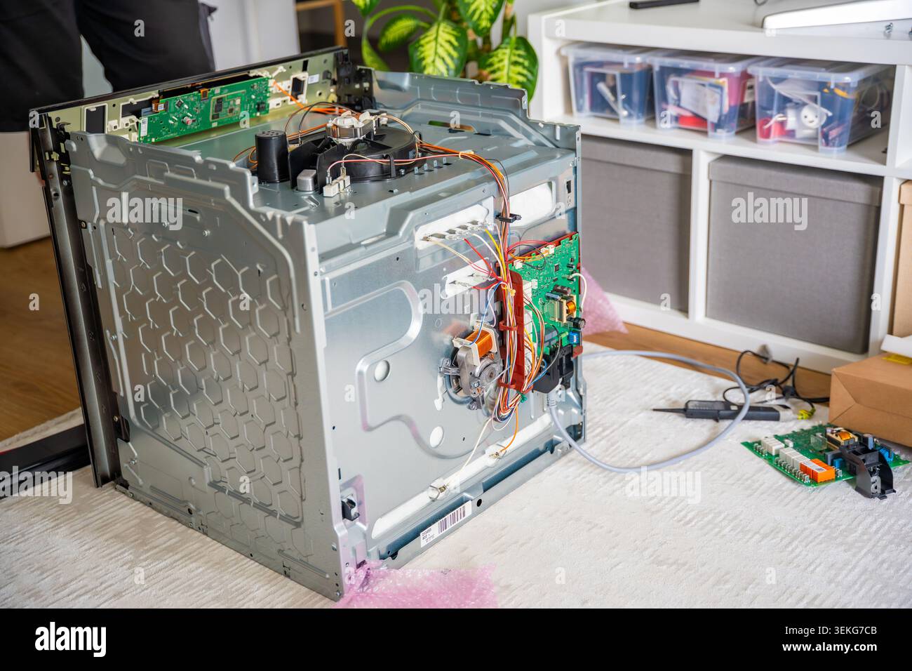 Area di lavoro per la riparazione di elettrodomestici con forno elettrico smontato e parti elettroniche di ricambio. Concetto di servizio professionale Foto Stock