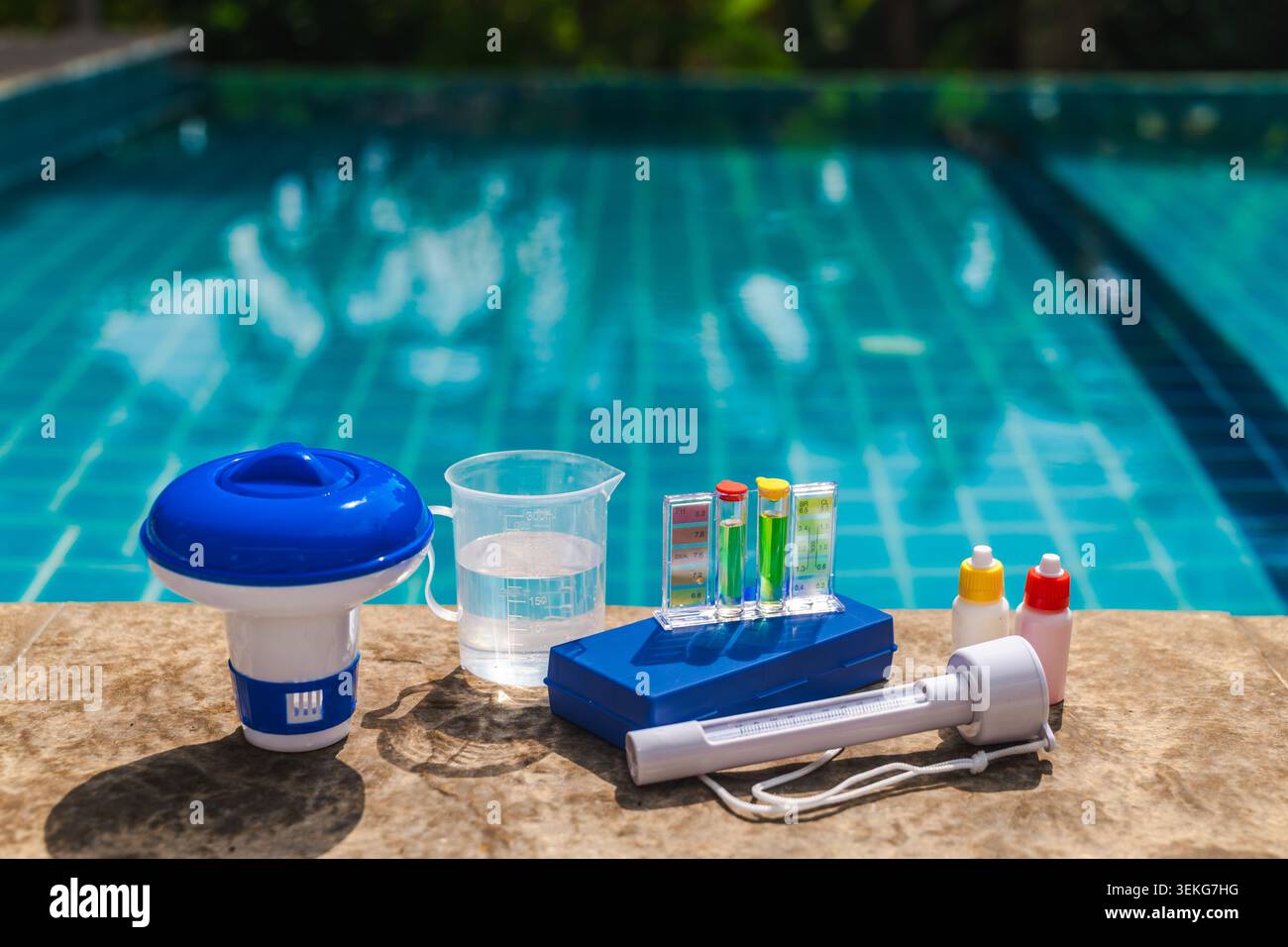 Sostanze chimiche liquide per piscine versate nell'acqua della piscina utilizzando un misurino trasparente con marcature di volume Foto Stock