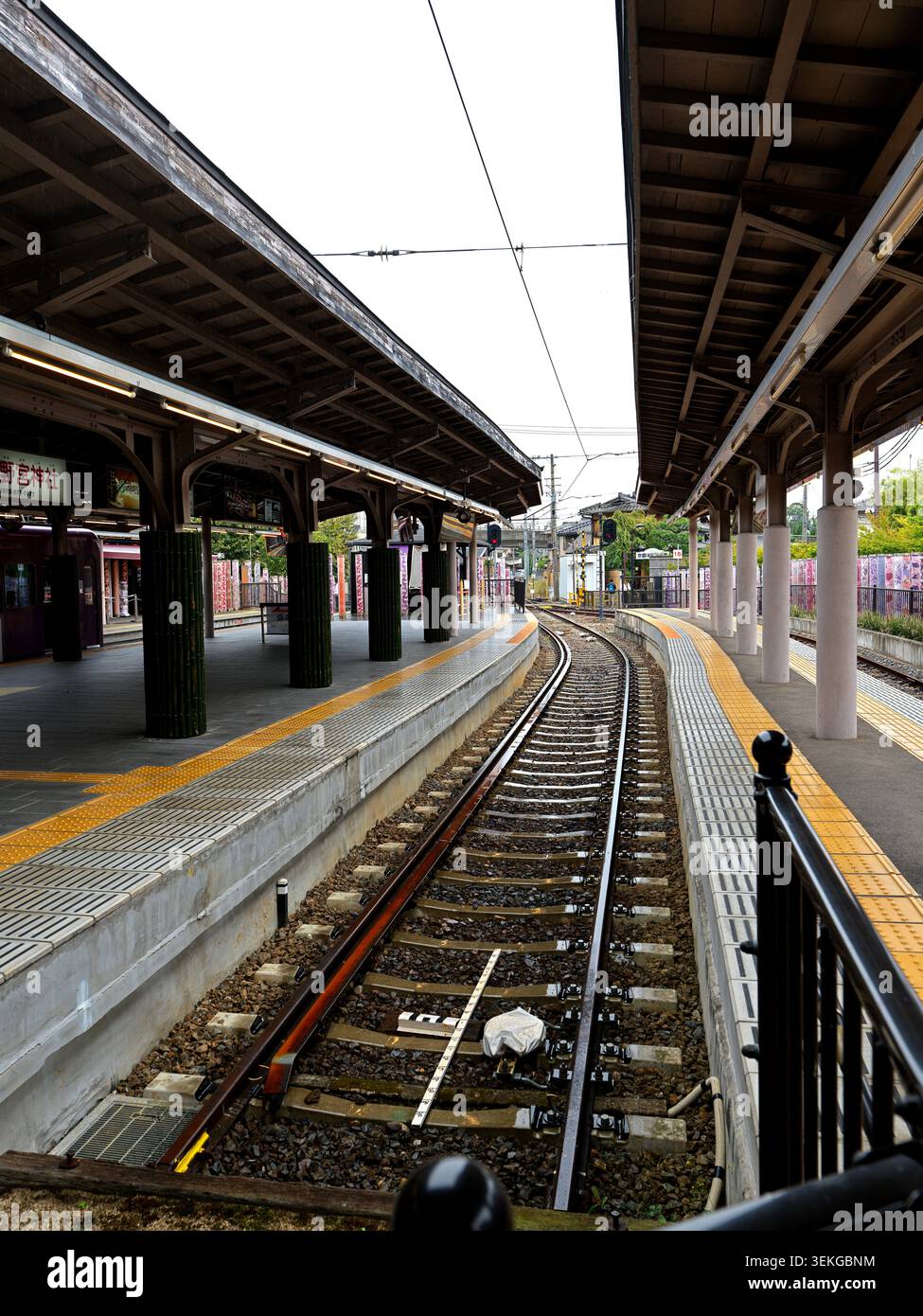 Binari curvi tra piattaforme coperte alla stazione di Arashiyama a Kyoto Foto Stock