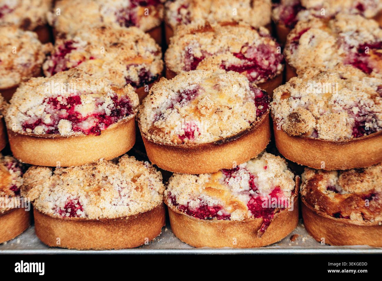 Crostate di fragole appena sfornate con crosta al burro, vivace ripieno di frutta e condimento dorato, disposte in file per mostrare pasticceria artigianale Foto Stock