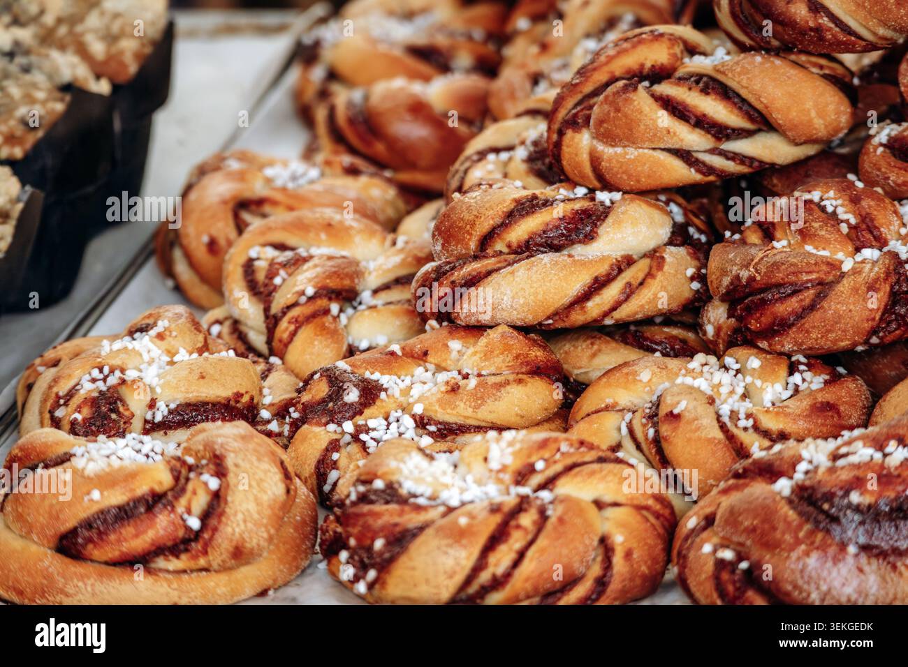 Dolci alla cannella appena sfornati con zucchero perlato, disposti in una vetrina di panetteria, con consistenza friabile, crosta dorata e SCA artigianale Foto Stock