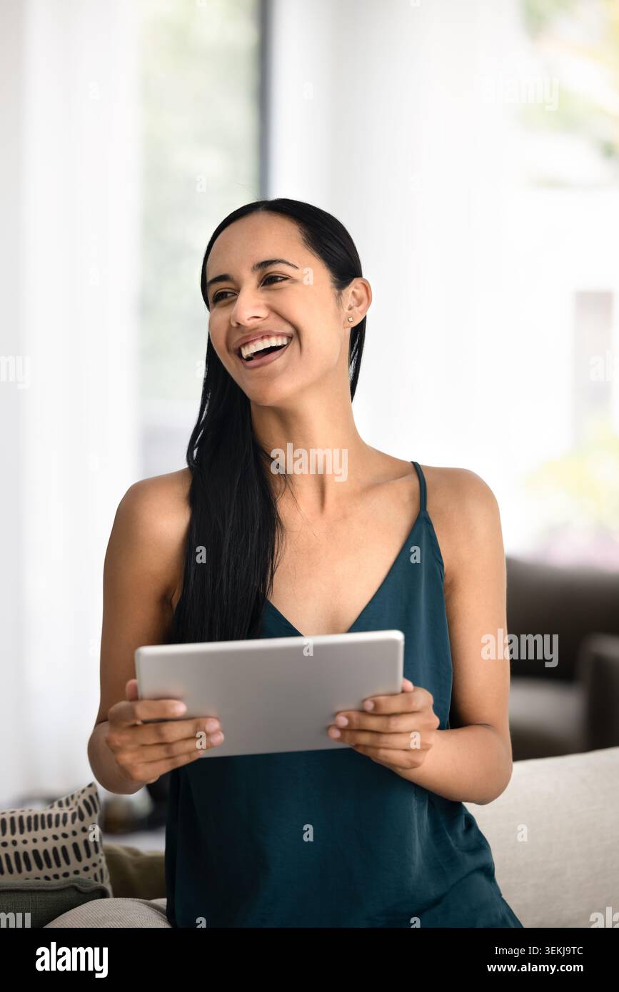 Donna felice con tavoletta digitale in casa Foto Stock