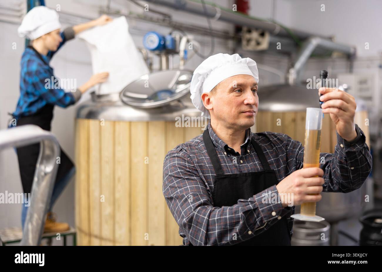Man Brewmaster che misura la birra con alcolometro Foto Stock
