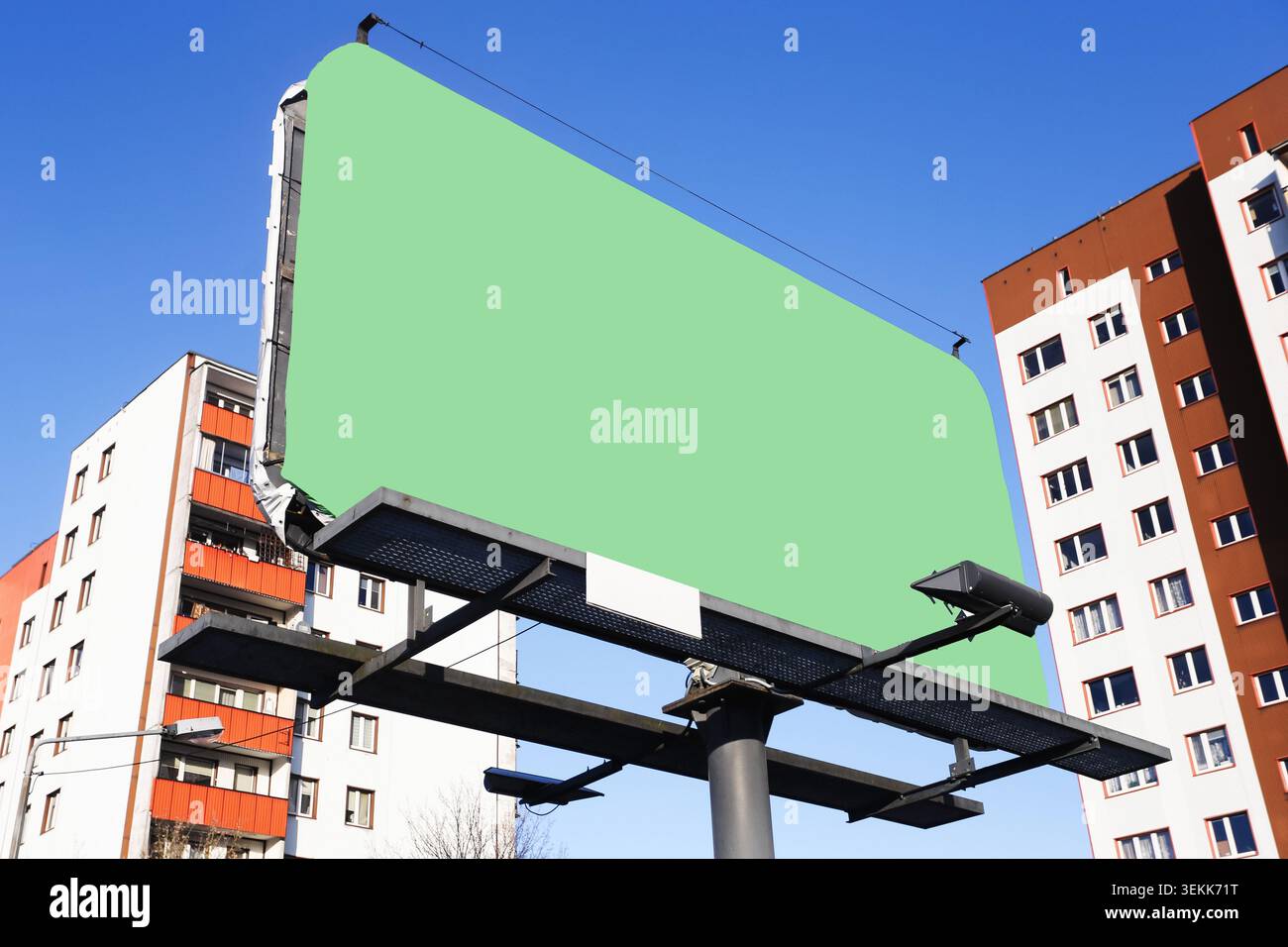 Grande tabellone verde che si trova accanto agli edifici residenziali sotto il cielo blu. Sfondo pubblicitario promozione marketing outdoor branding e spazio di testo. Foto Stock