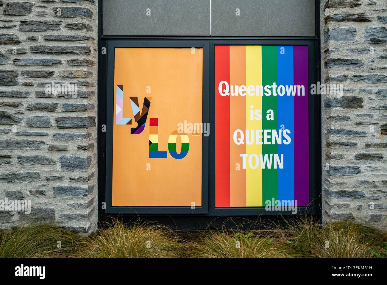 Una vetrina LGBTQ+ Pride all'ostello LyLo nel centro di Queenstown presenta una bandiera arcobaleno con il testo "Queenstown è una CITTÀ DEL QUEENS". Foto Stock