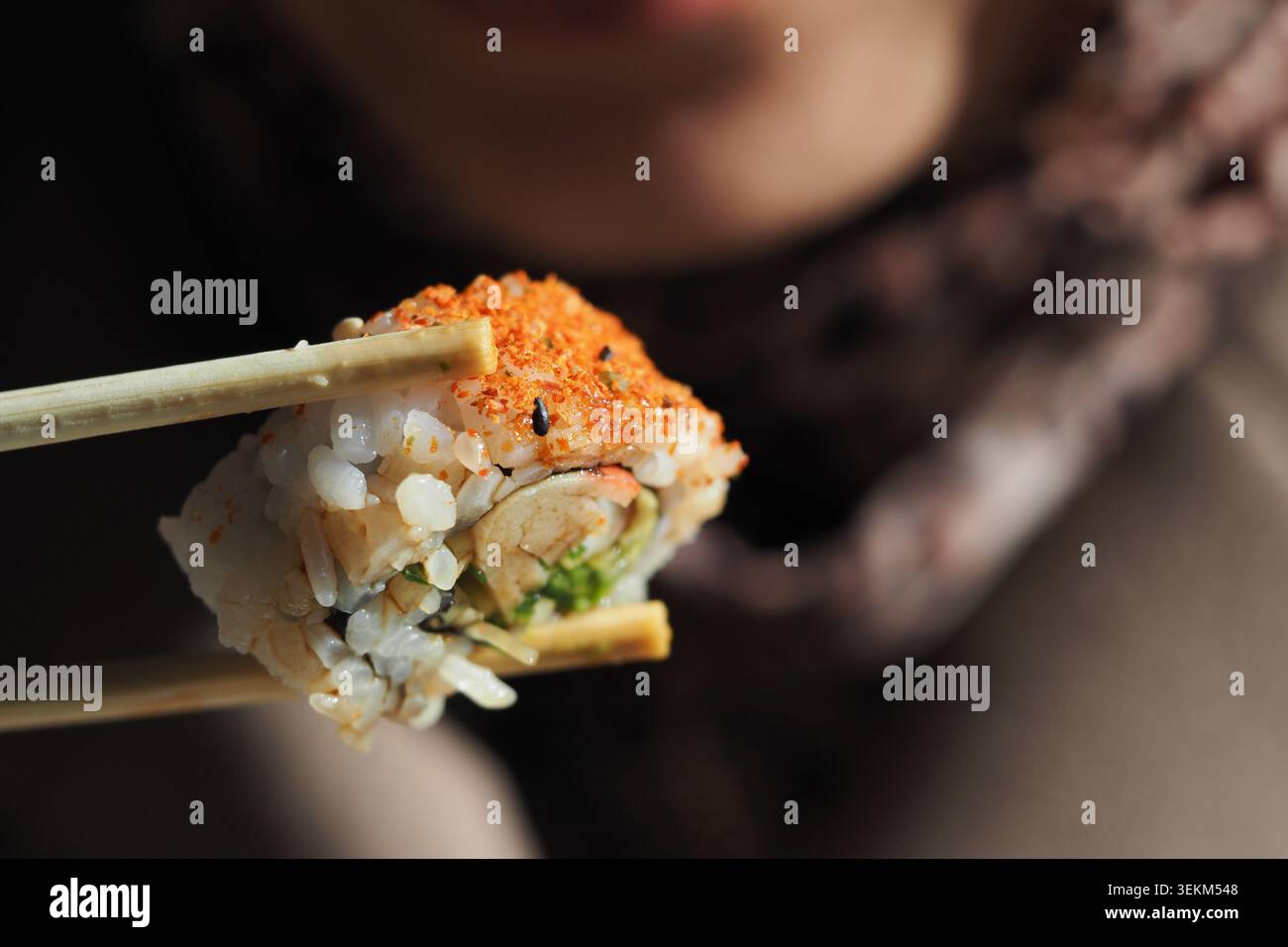 Mangiare sushi con bacchette in un ambiente informale Foto Stock