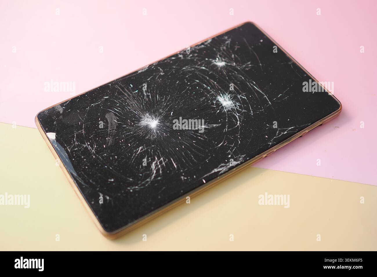 Smartphone con uno schermo incrinato su uno sfondo colorato Foto Stock