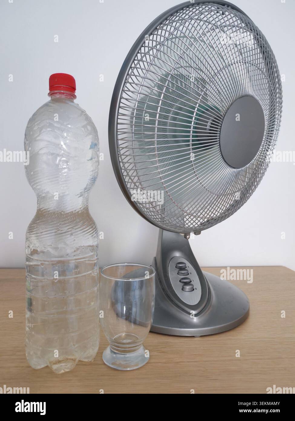 Ventilatori e bicchieri di acqua potabile per alleviare l'intenso calore estivo durante una giornata calda e umida al chiuso Foto Stock