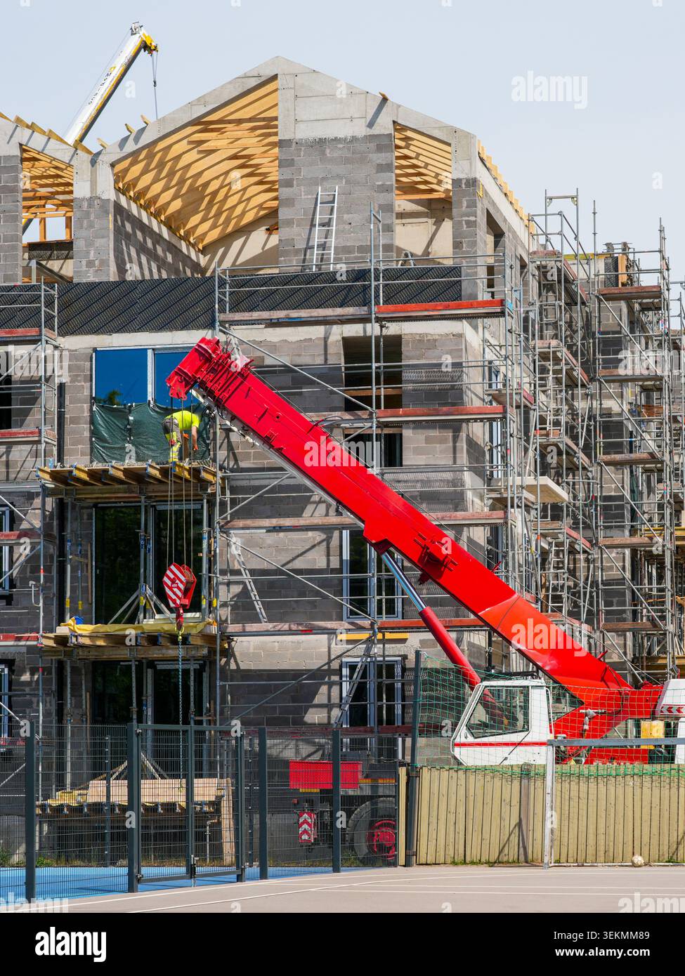 Costruzione di edifici residenziali multifamiliari con ponteggi con gru e struttura a tetto in legno Foto Stock