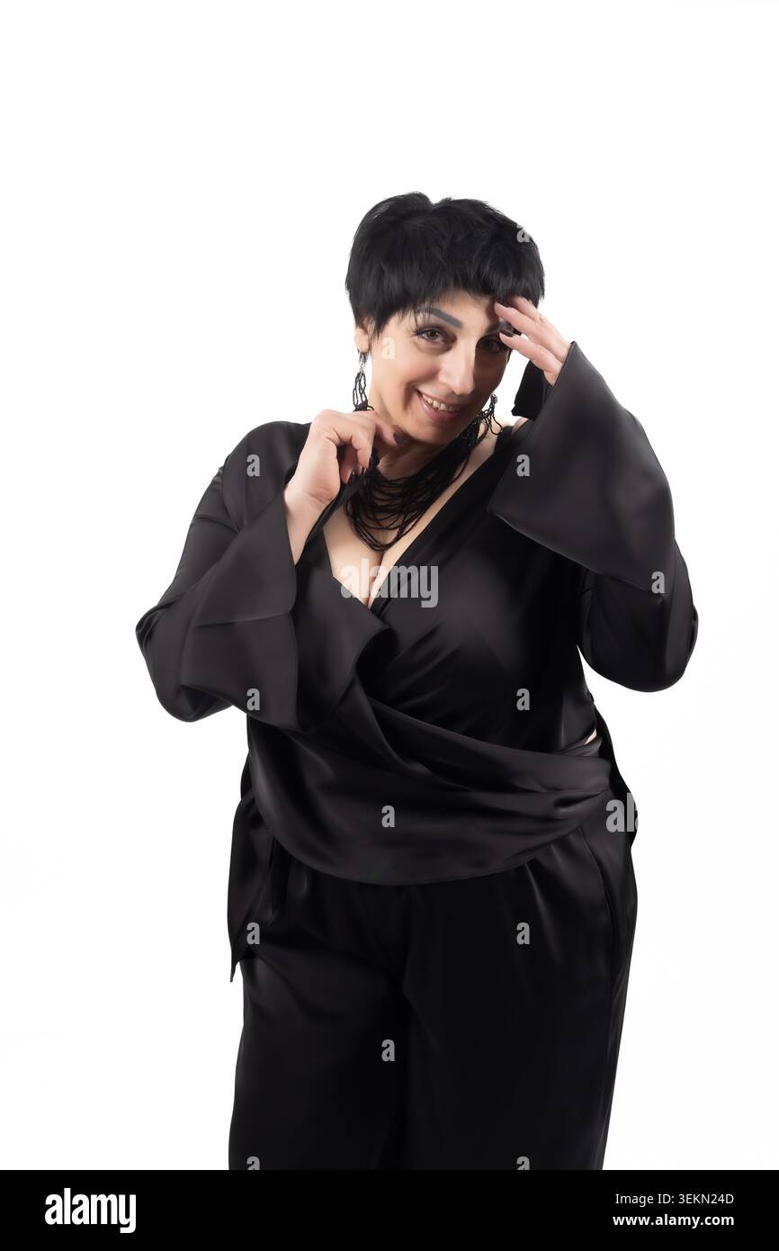 Elegante donna matura che tocca la sua collana d'argento con un sorriso Foto Stock