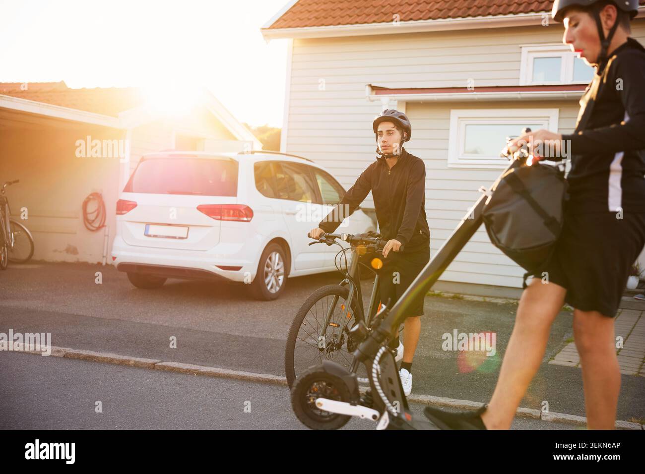 Ragazzi con mezzi di trasporto sostenibili sul vialetto Foto Stock