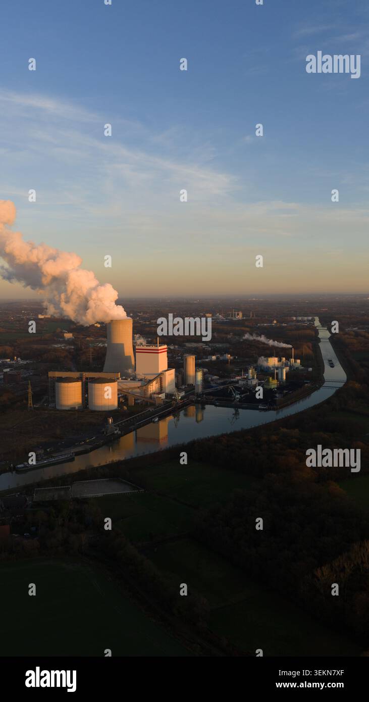 Centrale elettrica industriale che emette vapore al tramonto Foto Stock