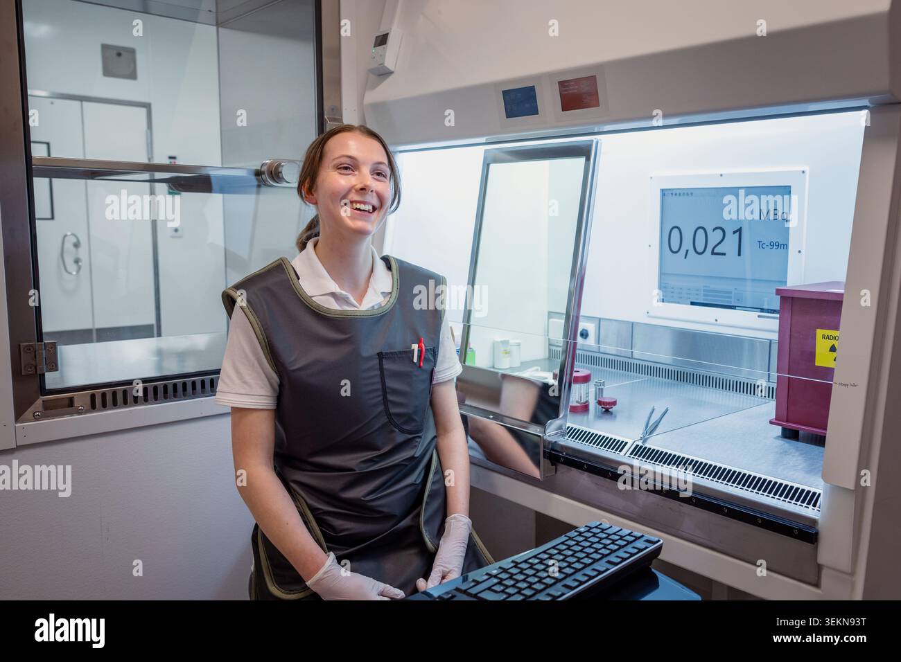 Scienziata sorridente seduta accanto all'armadietto laminare in laboratorio Foto Stock