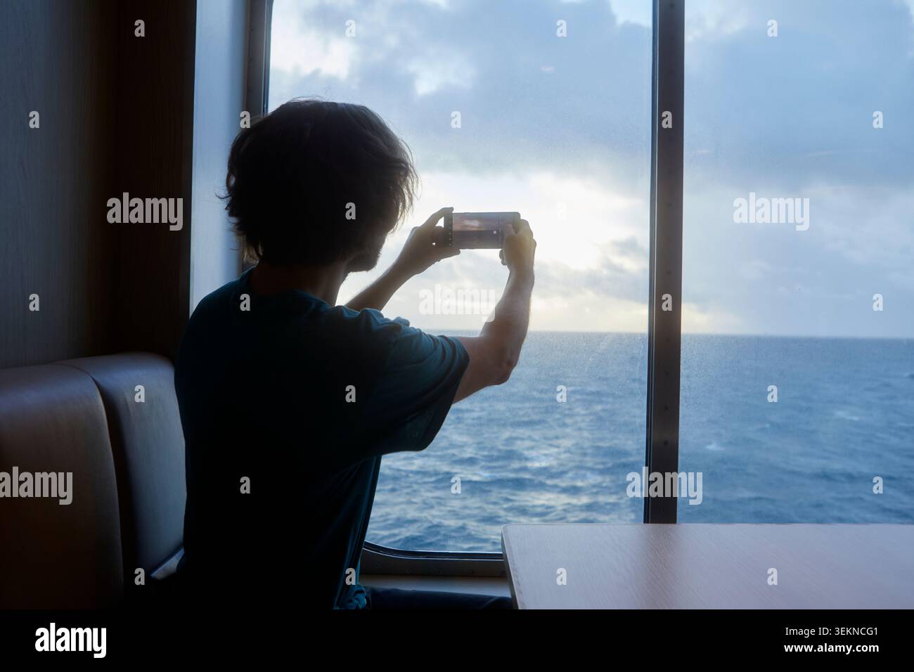 Vista posteriore dell'uomo che fotografa la vista del mare tramite smartphone mentre viaggia a bordo della nave Foto Stock