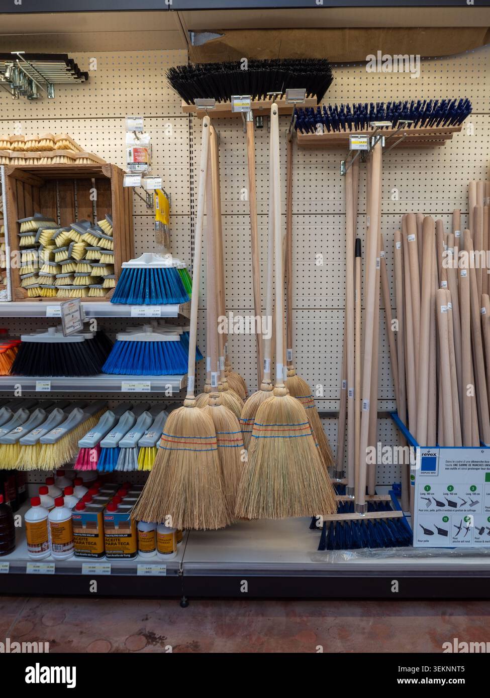 Cubelles, Spagna - 21 marzo 2026: Scaffale commerciale con spazzatrici in paglia tradizionali con manici in legno, spazzole in plastica e push Foto Stock