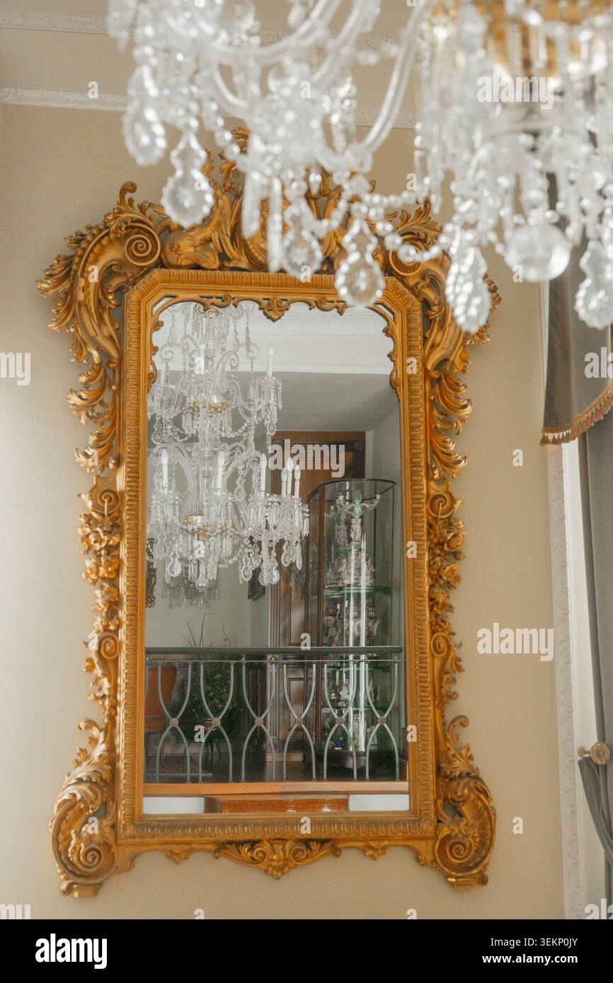 Specchio con cornice dorata nella tradizionale camera europea. Concetto di arredamento raffinato e stile storico. Foto Stock