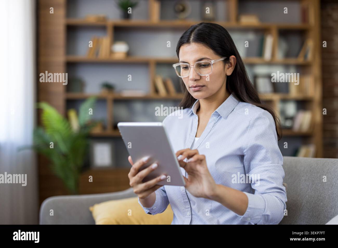 Giovane donna che utilizza con sicurezza un tablet digitale a casa, si connette con i colleghi, gestisce le attività e studia online per una carriera da freelance o un'istruzione remota Foto Stock