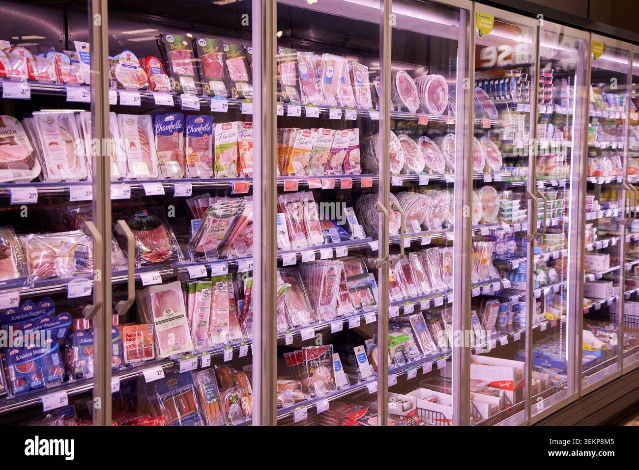 Espositori refrigerati pieni di carne, prosciutto e salsicce confezionati sugli scaffali di un supermercato o di un negozio di alimentari. Foto Stock