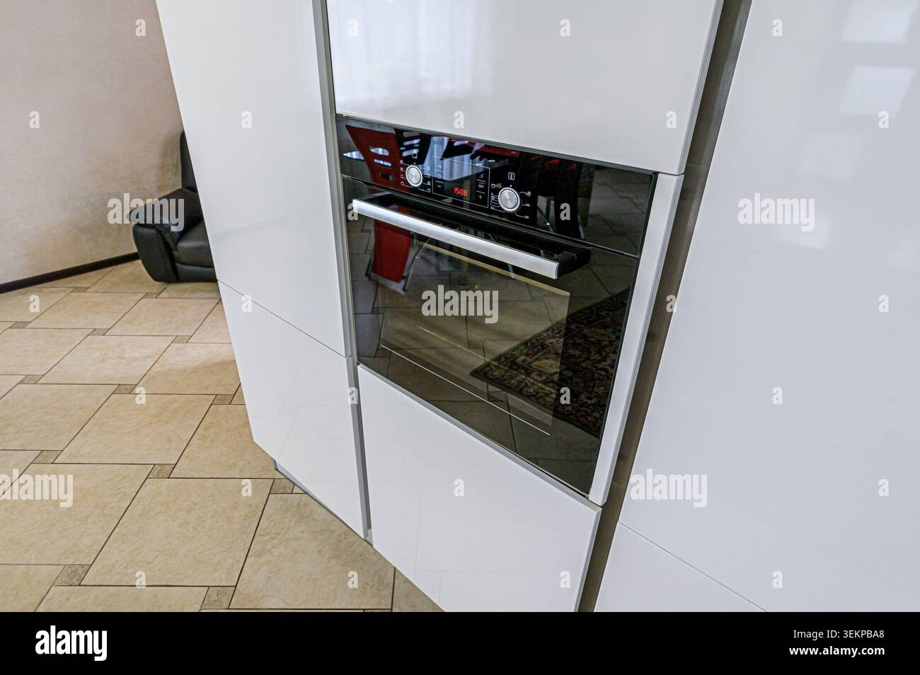 cucina moderna con forno a incasso in eleganti mobili bianchi. Il forno ha una parte anteriore in vetro nero con dettagli cromati. Foto Stock